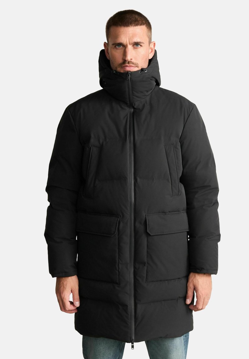Schwarzer Steppmantel mit hohem Kragen und verstellbarer Kapuze, ausgestattet mit vier Vordertaschen und Reißverschluss. Strukturierte, isolierte Optik.