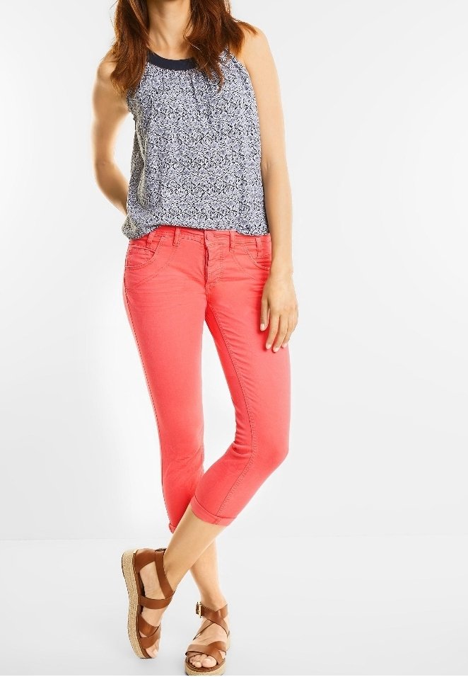 Top sin mangas de patrón azul y blanco combinado con pantalones capri color coral. Sandalias de tiras marrones. Tela suave y ajuste casual.