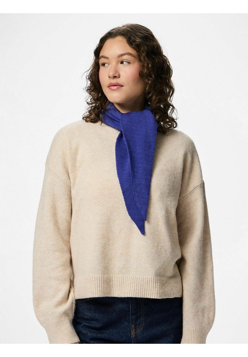 Blå tørklæde lavet af blødt stof, med en spids design, båret over en cremefarvet sweater. Tørklædet har en glat tekstur og falder elegant.