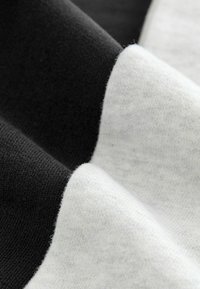 Baumwollmischgewebe in Schwarz und Weiß, mit einer weichen Textur, sichtbaren Strickmustern und sanften Falten, die kontrastierende Farben zur Schau stellen.
