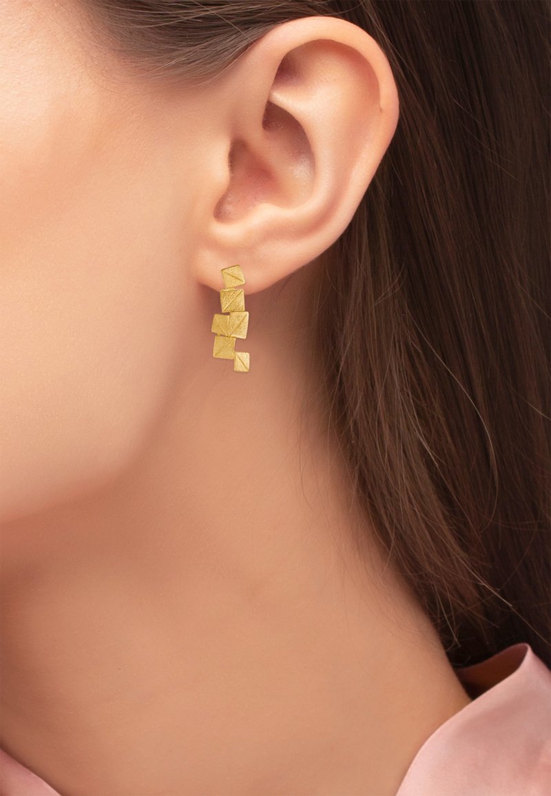 Gouden geometrische dangle oorbellen hebben stapelvormen van vierkanten met een gestructureerde afwerking, die elegant hangen aan een studbevestiging.
