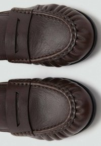 Mocasines de cuero marrón con un diseño acolchado, detalles texturizados y una parte superior suave con costuras. Sin herrajes visibles.