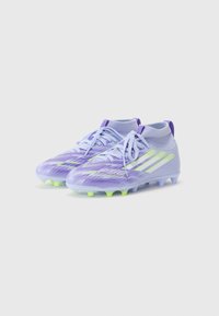 Des crampons de soccer violets avec une tige texturée, agrémentés d'accents vert néon et de trois rayures blanches. Conçus avec une silhouette profil basse.