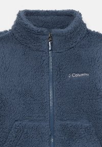 Giacca in pile di un blu navy scuro con chiusura a mezza zip, colletto alto e tessuto testurizzato e morbido; presenta un piccolo logo sul petto.