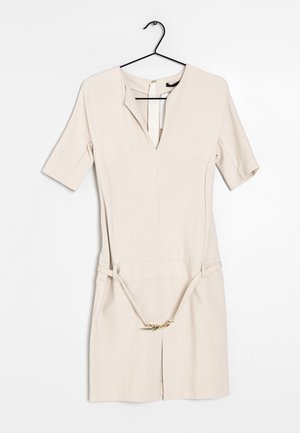 Beige korte mouwen jurk met V-hals en tailleceintuur, hangend aan een zwarte hanger tegen een witte achtergrond.