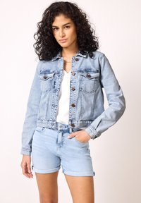 Giubbotto di denim blu chiaro con design fitted, chiusura a bottoni, tasche sul petto e maniche lunghe, abbinato a pantaloni corti di denim blu chiaro.