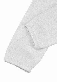 Lys grå hettegensererm sleeves med et mykt, teksturert stoff. Har en rynket mansjett for en tett passform. Glatte sømmer langs kanten.