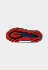 Suela de zapato con un diseño multipatrón en secciones rojas y negras, texturizado para agarre y con una forma aerodinámica para el rendimiento.