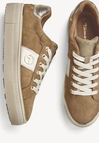 Bruna mockaskinnssneakers med en vit accentrand, guldlogotypdetalj, vita snören och en texturerad gummisula.