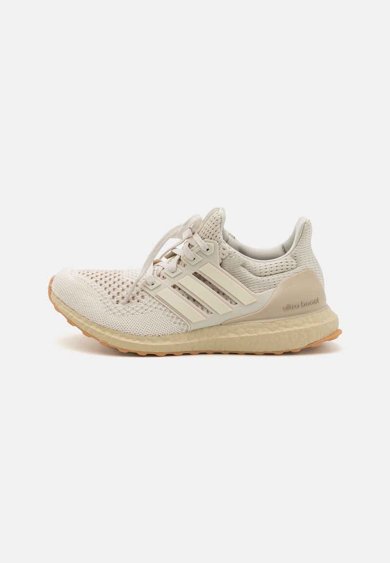 Světle béžová sportovní obuv s prodyšným síťovaným svrškem, třemi bílými pruhy a texturovanou gumovou podrážkou. Obsahuje branding 'ultra boost'.