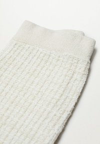 Witte, gestructureerde sokken met een geribbelde uitstraling en een effen, dikkere boord. Zacht materiaal met een weelderig gevoel en subtiel ruitpatroon.