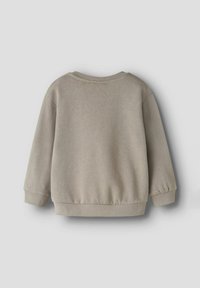 Gaiši bēšs džemperis ar apaļu kakla izgriezumu, garām piedurknēm un ribotu apdari piedurknēs. Mīksta tekstūra un brīvs siluets, noapaļota, vienkārša aizmugure.