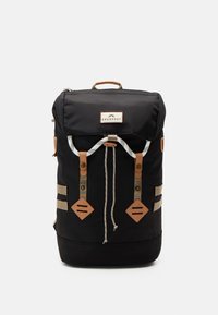 Svart stoff ryggsekk med brune skinnaksenter, rulloppdesign, metalltilbehør og to frontstropper for sikker lukking.