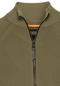 Olivengrøn zip-up jakke med ribbet tekstur, høj krave og kontrastfarvet orange indvendig foring; har en sort lynlås med et struktureret træk.