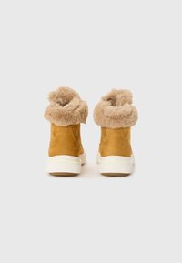 Gule semskede ankelstøvler med en beige faux fur mansjett og hvit gummisåle, som viser en avrundet tå og et minimalistisk design.