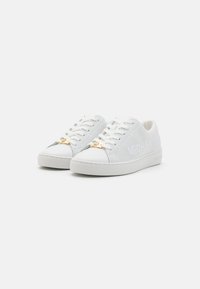 Hvide sneakers med en mesh-overdel, rund tå og en glat gummisål. Guldhardware-accent på tungen, med logo-detalje på siden.