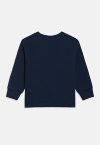 Tengerészkék hosszú ujjú, kerek nyakú pulóver bordás mandzsettákkal, fehér háttéren hátulról bemutatva.