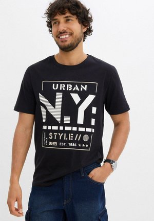 T-shirt in cotone nero con grafica bianca che riporta il testo "URBAN N.Y. STYLE// USA EST. 1986". Maniche corte e scollatura rotonda.