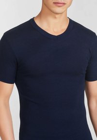T-shirt a maniche corte blu navy realizzato in un tessuto morbido e elasticizzato, con scollo a V e silhouette aderente.