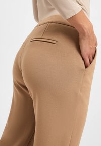 Tan katoenmix broek met een gladde textuur, voorzien van achterzakken, een aangesloten taille en een relaxte uitstraling.