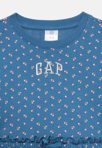 Sweatshirt azul para criança com pequenas estampas florais em rosa e branco, com a palavra "GAP" bordada em letras prateadas e um acabamento com pregas na parte inferior.