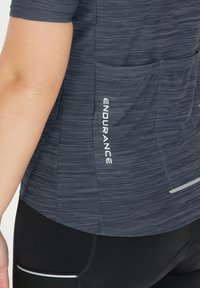 Mörkgrå sporttröja med texturerad tyg, korta ärmar, bakficka och "ENDURANCE"-logotyp i vitt.
