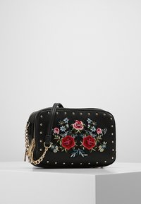 Borsa in finta pelle nera con rose ricamate e fiori blu. Presenta borchie dorate e una tracolla a catena removibile. Chiusura con cerniera.