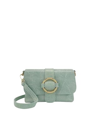 Petit porte-monnaie bracelet en daim vert pastel avec un fermoir circulaire doré et une bride de poignet assortie sur fond blanc.