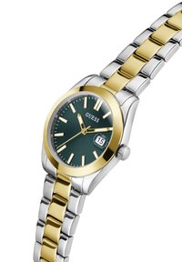 Montre Round Guess avec un cadran vert, des accents dorés et un bracelet en acier inoxydable argenté. Les caractéristiques incluent des marqueurs d'heure et un guichet de date.