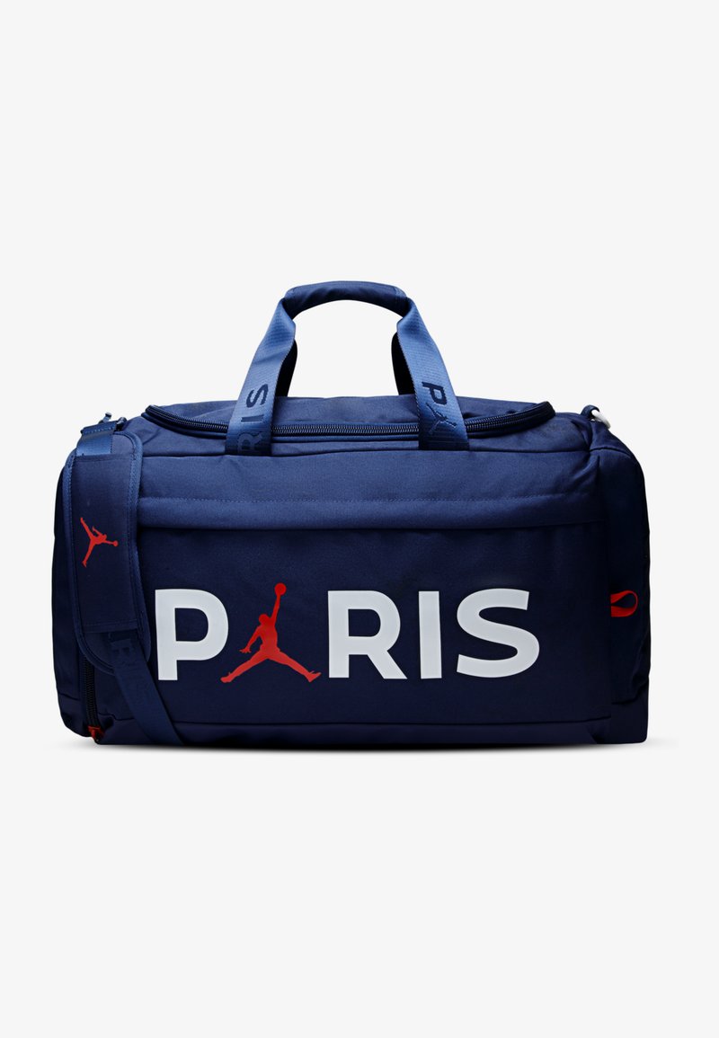 Bolsa marinera azul marino con "PARIS" en grandes letras blancas y logo rojo de Jordan. Cuenta con asas dobles y una correa ajustable para el hombro.
