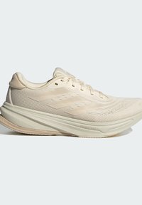 Beige hardloopschoenen met een gestructureerde bovenkant, een gevoerde zool en een golvende design op de tussenzool. Voorzien van platte veters en een gewatteerde kraag.