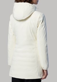 Giacca invernale color crema con un design aderente, cappuccio e texture liscia. Presenta maniche lunghe e lunghezza fino a metà coscia.