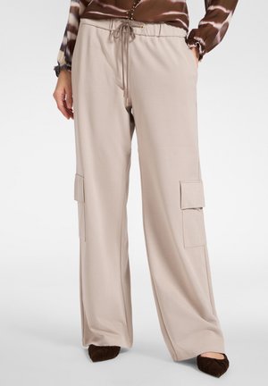 Beige weite Cargo-Shorts mit elastischem Bund, Kordelzug und zwei seitlichen Taschen. Weicher Stoff mit glatter Textur.