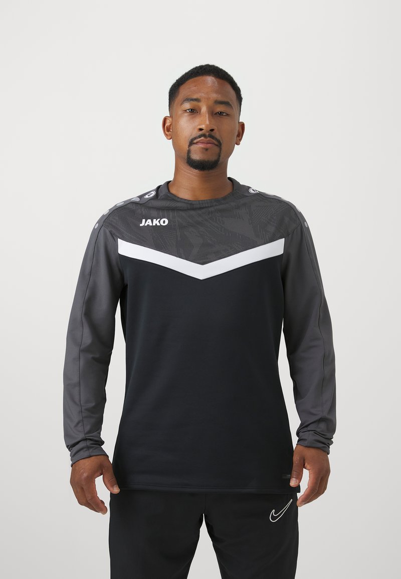 Maglia atletica a maniche lunghe in nero e grigio con design a chevron; presenta un tessuto testurizzato e un logo sul petto con dettagli sulle spalle.