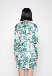 Sukienka z satyny w kolorze białym z żywym turkusowym wzorem kwiatowym, z długimi rękawami i kołnierzykowym dekoltem.