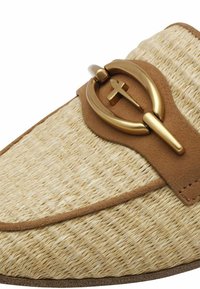 Woven straw slip-on shoe in beige, featuring a tan suede strap and a gold metal buckle with a cross detail. Smooth texture and rounded shape.