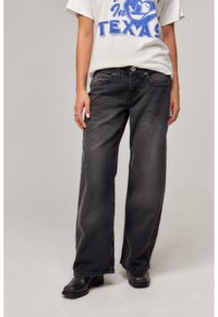 Black wide-leg denim jeans with a faded finish, featuring a five-pocket design and a button-and-zip fly closure, paired with black ankle boots.