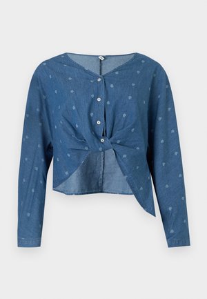 Sinine pikkade varrukatega lühike pluus väikeste heledate paisley-trükkidega, ees nööbid ja vöökohal keeratud sõlm.