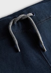 Jogging en mélange de coton bleu marine avec une taille texturée, un cordon de serrage gris avec des embouts métalliques, et des détails de couture le long de la taille.