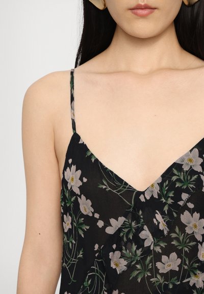 Robe noire à fleurs avec des bretelles fines, présentant un décolleté en V et de délicats motifs de fleurs pastel sur un fond noir. Tissu doux et léger.