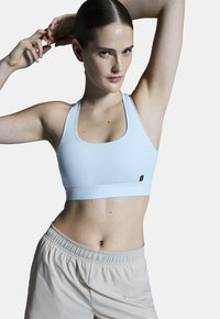 Hellblauer Sport-BH mit quadratischem Ausschnitt und Racerback-Design. Hergestellt aus glattem, dehnbarem Stoff und mit einem kleinen schwarzen Logo auf der Vorderseite.