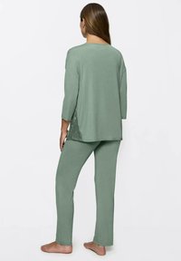 Conjunto de ropa de casa verde que incluye una camiseta de corte holgado con mangas tres cuartos y pantalones de pierna recta, confeccionado en un tejido suave y transpirable.