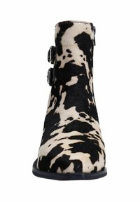 Bottine en cuir de vachette avec un motif noir et beige, dotée de deux boucles noires sur le côté. Texture lisse et design à bout rond.