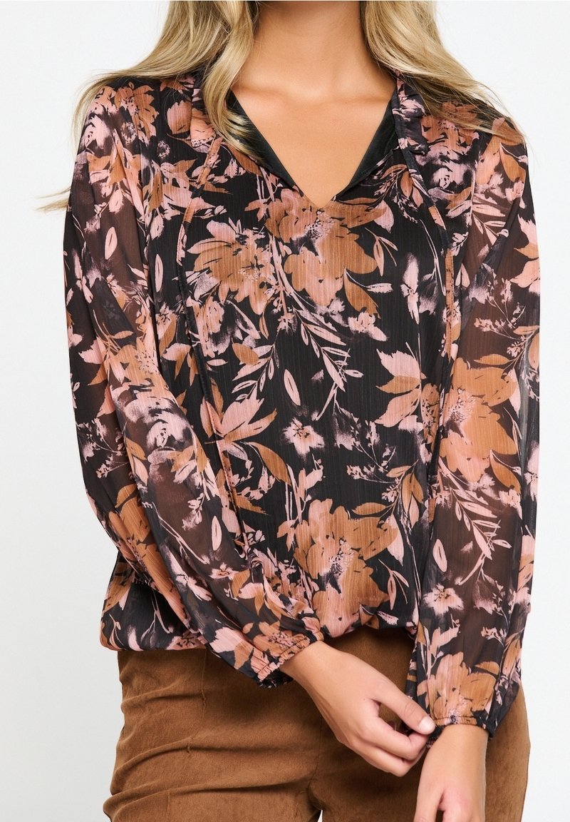 Blouse florale en tissu noir transparent avec des motifs floraux roses et bruns. Dotée d'un décolleté en V et de manches bouffantes avec des poignets élastiques.