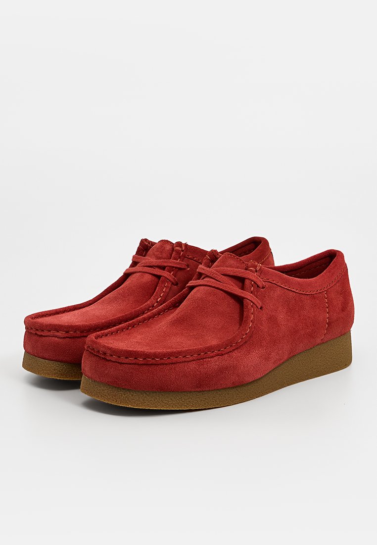 Rote Wildlederschuhe mit runder Zehenpartie und genähten Details, ausgestattet mit einer niedrigen braunen Plattformsohle und Schnürverschluss.