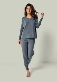 Graues Loungewear-Set mit einem lässigen, V-Ausschnitt Langarmshirt und elastischen Bundhosen, beide aus weichem, strukturiertem Stoff.