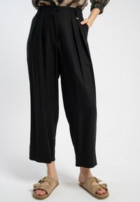 Czarne plisowane spodnie o wysokim stanie, szerokich nogawkach i kieszeniach; wykonane z gładkiego materiału o czystym wykończeniu oraz delikatnym detalem w postaci metalowych elementów.