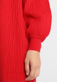 Rode gebreide trui met een textuurpatroon. Heeft puffed sleeves en geribbelde manchetten. Gladde brei stof met een warme, zachte uitstraling.