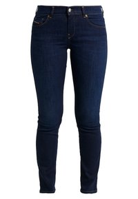 Mörkblå denim skinny jeans med en slät yta, femfickorsdesign och detaljer i gul söm. Har knappstängning i metall fram.