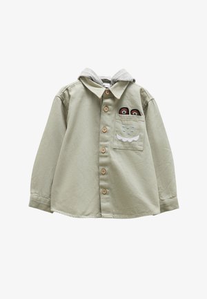 Světle zelená košile na knoflíky s šedou mikinou. Má dřevěné knoflíky a přední kapsu s vyšitými detaily postavy.